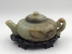 A Chinese jade teapot on a carved hardwood stand. W.22 D.15 H.10cm.