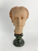A terracotta bust of a young girl raised on a marble socle. H.39cm