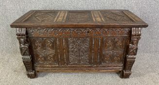 An 18th century oak coffer with carved panels flanked by figural pilasters. H.58 W.110 D.51cm