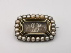 A Georgian yellow metal (tests as 9ct) seed pearl, black enamel and hair mourning brooch. The rock