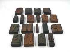 A collection of nineteen wooden type letter blocks. H.8 W.8cm (largest).