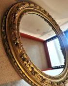 A large 19th century French carved giltwood and gesso wall mirror with scrolling foliate and oak