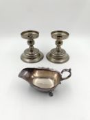 A pair of silver plated candlesticks and a silver plated gravy boat. H.13cm (largest)