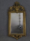 A 19th century giltwood and gesso wall mirror with scrolling foliate cresting and bevelled plate.