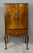 A mid century burr walnut cocktail cabinet with satin birch and glazed interior, mixing slide and