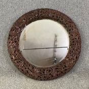 An Eastern carved hardwood wall mirror with bevelled plate. Dia.95cm