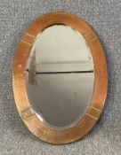 An Arts and Crafts style embossed copper wall mirror in an oval bevelled plate. H.69 W.47cm