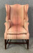A Georgian style high back wing armchair in striped damask on mahogany supports. H.108 W.58 D.63cm