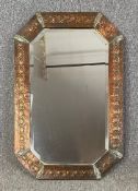 An Arts and Crafts style embossed copper wall mirror in a shaped bevelled plate. H.82 W.54cm