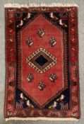 A Hamadan rug with central hooked diamond medallion on a burgundy ground within stylised spandrels