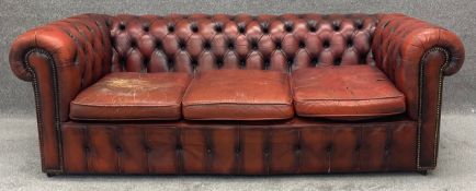 A three seater Chesterfield sofa in leather upholstery. H.69 W.204 D.100cm (Wear and tear as seen).