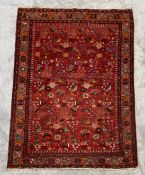 A Kashan style carpet with bird and foliate decoration across a burgundy field within boteh and