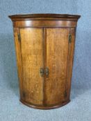 A Georgian oak bow fronted corner cupboard. H.108 W.74 D.51cm