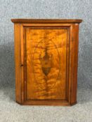 A Georgian satinwood and inlaid corner cabinet with classical style urn to the panel door. W.58 H.73