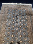 A Bokhara carpet with repeating gul medallions on a powder blue ground within multiple geometric