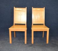 A pair of light oak ecclesiastical hall chairs.