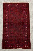 A hand made Afghan rug, with all over stylised foliate decoration on a claret ground. L.189 W.107cm
