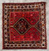 A hand knotted Kazak with burgundy ground in stylised borders. (Cut and sewn to square). L.164 W.
