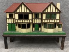 A large vintage hand built Tudor style doll's house by Tri-ang on an oak stand. H.92 W.123 D.49cm