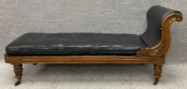 A mid 19th century carved faux rosewood chaise longue with leather upholstery raised on tapering