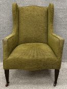 An Edwardian wingback armchair with square tapering legs on castors velour upholstery. H.110 W.73