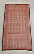 A hand knotted flatweave North African carpet with all over geometric pattern on a burgundy field.