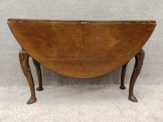 A mid Georgian oak drop flap dining table with shell and husk carving on pad foot cabriole supports.