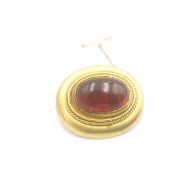 An Etruscan revival 15ct yellow gold garnet brooch, set to the centre with a foil backed oval