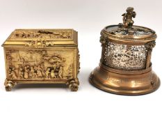 An A. B. Paris brass casket box depicting village life in relief with a cushioned fabric interior,