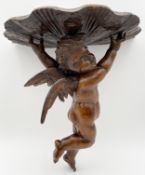 A carved wall bracket in the form of a winged cherub. H.36 W.34 D.20cm