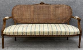 A Louis XVI style carved beech canape sofa with caned back and upholstered seat. H.99 W.168 D.66cm