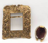 A gilt metal picture frame with winged cherub decoration in relief and a small brass easel mirror.