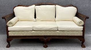 A vintage carved mahogany bergere sofa with scrolling arms, on squat cabriole legs with ball and
