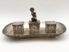 A hallmarked silver desk stand with twin inkwells and a central candlestick, each fitted with