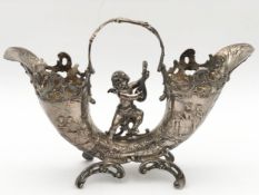 A hallmarked silver cornucopia epergne decorated with Rococo scrolls and a winged cherub playing a