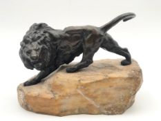 In the manner of Prosper Lecourtier, a bronze figure of a lion on a naturalistic rocky outcrop base.