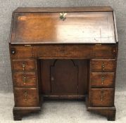 A Georgian country oak kneehole writing bureau with brass handles and a fitted interior on shaped