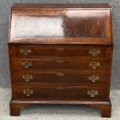 A Georgian burr walnut writing bureau with pierced brass handles and escutcheons, and a shaped and