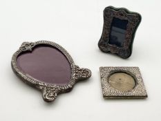 A collection of three silver miniature embossed picture frames to include one heart shaped with a