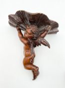 A carved wall bracket in the form of a winged cherub. H.33 W.34cm