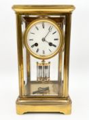 A late 19th century French brass four glass mantle clock with a moulded cornice and inset bevelled