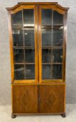 An early 20th century walnut bookcase raised on bun feet with a moulded and shaped cornice above two