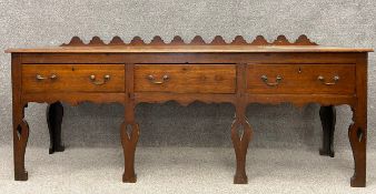 A Georgian country oak dresser with three frieze drawers with brass handles, raised on shaped and