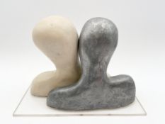 Two abstract resin busts, talking heads, on a clear perspex base. H.21 W.28 D.12.5cm.