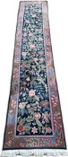A wool runner in the style of William Morris, with a floral and foliate design over a dark blue