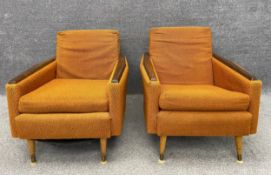 A pair of mid-century Danish style armchairs with teak armrests and tapering feet, with original