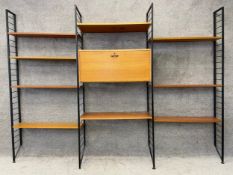 A mid century Staples Ladderax modular shelving system comprising four black uprights, nine teak