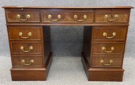 A Georgian style double pedestal desk with cockbeaded drawers, brass handles and an embossed and