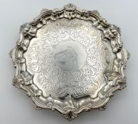 A silver card tray with English hallmarks (rubbed) with scalloped edge raised on three feet. Dia.