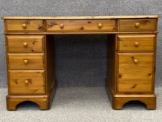 A contemporary pine double pedestal desk with an embossed and gilt leather top, on shaped bracket